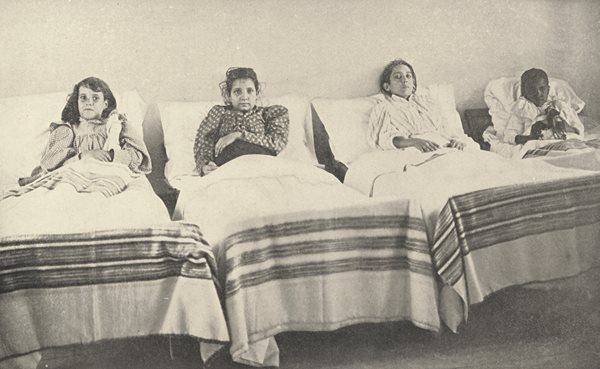 four children sitting up in hospital beds
