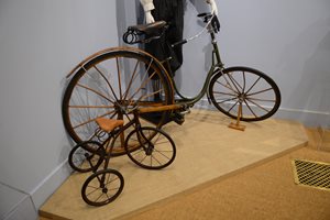 Ladies bicycle with wooden spokes and fenders next to child’s tricycle