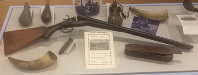 Case display of various artifacts: shotgun, horns, flask, game caller
