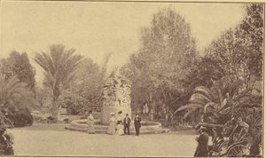 historic photo showing 5 people in front of statue in park