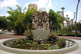 modern photo of statue in center of small pond surrounded by sidewalk