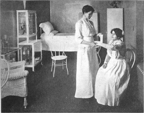 hotel infirmary, one woman seated being treated by another woman standing, bed and chair in background