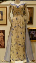 floor length satin gown with intricate beading on white mannequin