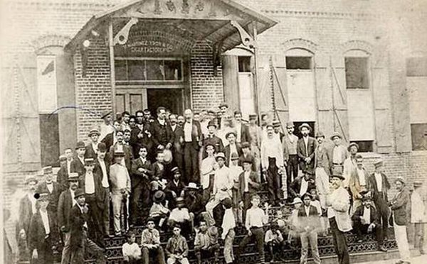 men and boys in front of entry to factory