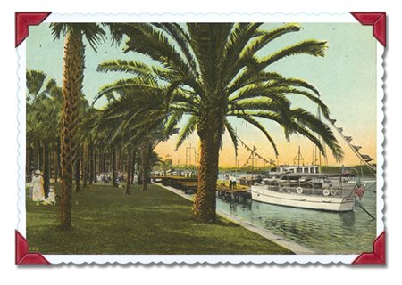 sailboat moored at a dock on a river, view from grassy area in park