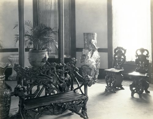 historic photo showing bench carved to look like briar roots. two ornate chairs in background of Hotel Grand Salon